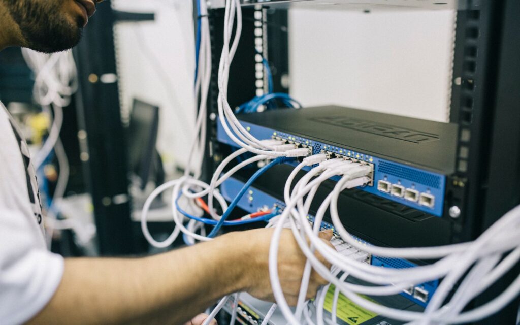 Tecnico collega cavi di rete a uno switch in un armadio rack